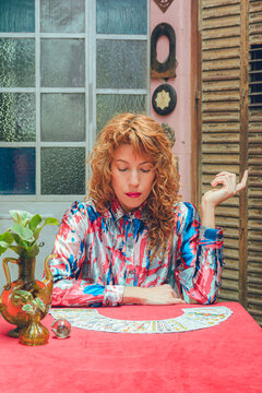 tarot reader woman sitting looking at cards on table thinking, vertical image
