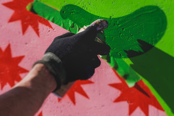 Process of creating graffiti, street artist with aerosol spray paint painting colorful stencil...