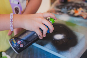Process of creating graffiti, street artist with aerosol spray paint painting colorful stencil...