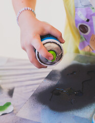 Process of creating graffiti, street artist with aerosol spray paint painting colorful stencil...