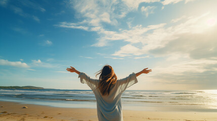 空と海が綺麗なビーチに立って、海と空に向かって手を広げている女性