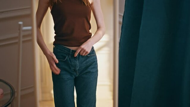 Female reflection checking weight loss progress. Smiling woman trying big jeans