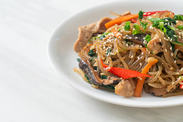 japchae or stir-fried Korean vermicelli noodles with vegetables and pork topped with white sesame