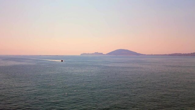 Seascape at Sunset with speedboat swimming fast on calm waves, summer day