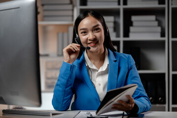 Asian woman wearing headphones and talking to customers. Call center employees answer the phone to...