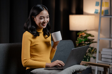Fototapeta premium Asian woman relaxing on sofa in house, businesswoman spends her vacation watching movies, listening to music and surfing social media on smartphone, texting and chatting with friends. Weekend concept.