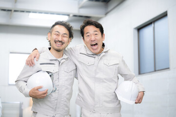 Obraz premium Two very friendly workers with helmets and smiles Yeah with the image of changing jobs and hiring! Looking at the camera 