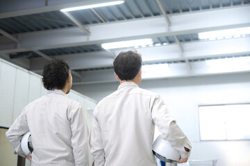 倉庫で働く見上げる作業員の顔無しの後ろ姿　製造業や配送業などのイメージ