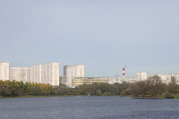 Naklejka premium View of residential buildings on the shore of a pond in a landscape park, Yuzhnoye Butovo, Moscow, October 2023.