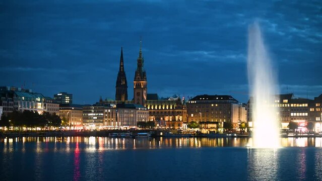 Time lapse of Hamburg's Alster Lake, where the Alster fountain takes center stage, surrounded by the impressive backdrop of the iconic Hamburg skyline and the bustling urban life. Rowers on the Alster