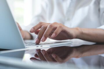 Close up of business woman hand typing on laptop computer keyboard with reflection on digital...