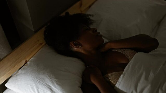 African american woman lying on bed suffering neck pain at bedroom