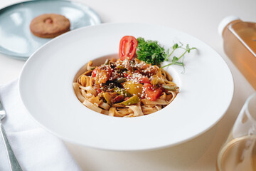 udon noodles with sesame seeds and herbs in a white plate side view