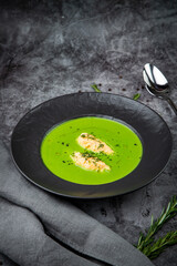 broccoli cream soup with pieces of chicken fillet on a dark background