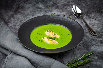 broccoli cream soup with pieces of chicken fillet on a dark background