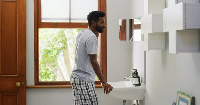 Black man, morning in bathroom and grooming, hair care and wellness with routine and beauty at home. Hygiene, fresh and check hairstyle in mirror with cosmetics, clean and natural with texture