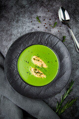 broccoli cream soup with pieces of chicken fillet on a dark background top view