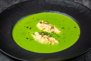 broccoli cream soup with pieces of chicken fillet on a dark background
