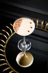 iced latte with foam in a martini glass on a dark background