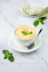 cup of coffee with foam and a sprig of mint on a marble background