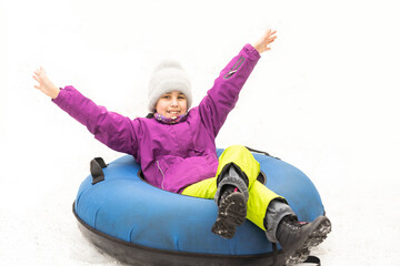 Child riding on tube, little girl during tubing in winter park