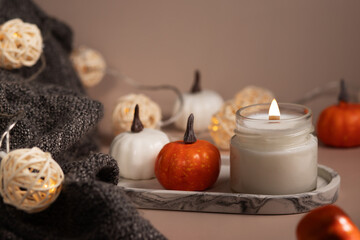 candle burning in in home interior, warm blanket and autumn pumpkins, soft and warm light for relaxation