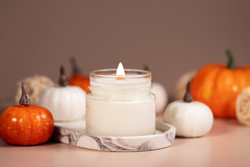 Aromatherapy in the home interior with Candle with autumn pumpkins, autumn atmosphere with warm lights