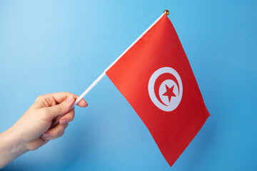 Tunisian flag in hand on a blue background, copy space, independence national day of Tunisia, country freedom, patriotism