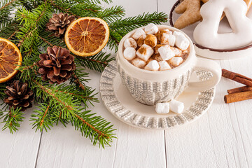 Beautiful cup with New Year knitted pattern with hot cocoa or chocolate drink with marshmallows on white wooden table. concept of cozy Christmas