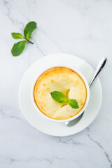cup of coffee with foam and a sprig of mint on a marble background top view