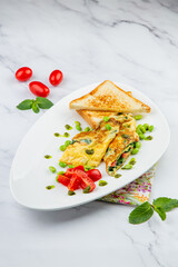 Breakfast of eggs and vegetables with cherry tomatoes and slices of bread in a white plate side view