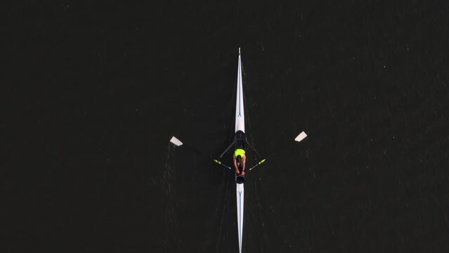 Drone footage over a male athlete sculling in a tranquil river on a sunny day