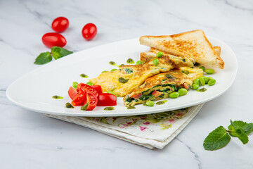 Breakfast of eggs and vegetables with cherry tomatoes and slices of bread in a white plate side view