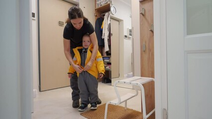woman dresses her toddler child in warm clothes before heading out into the cold weather