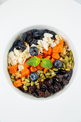 deep plate with cereals, berries, pistachios, dried apricots and raisins top view