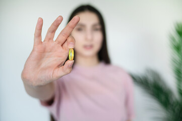 A happy girl in a pink T-shirt, a brunette, holds in her hands a lump of fallen dark hair and a remedy against baldness on her hands, close-up. Vitamin deficiency and hair loss