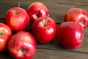 Red apples on a wooden table. Autumn apples are red in color. A few scarlet apples.