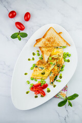 Breakfast of eggs and vegetables with cherry tomatoes and slices of bread in a white plate top view