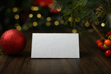 Blank invitation card on wooden table with Christmas ornaments. Blank business card mockup.