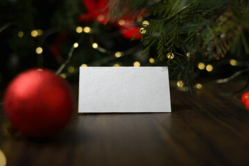 Blank invitation card on wooden table with Christmas ornaments. Blank business card mockup.