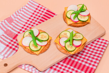 Light Breakfast. Quick and Healthy Sandwich. Fresh Cucumber and Radish with Green Onions and Cheese on Crispy Cracker on Wooden Cutting Board