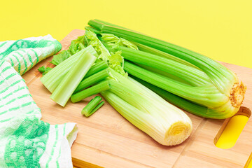 Fresh Celery Stem and Chopped Celery Sticks on Wooden Cutting Board. Vegan and Vegetarian Culture. Raw Food. Healthy Diet with Negative Calorie Content. Slimming Food