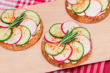 Light Breakfast or Diet Eating - Crispy Cracker Sandwich with Cream Cheese, Fresh Cucumber and Radish on Wooden Cooking Board on Magenta Background