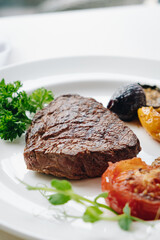 beef steak with grilled vegetables and herbs on a light background