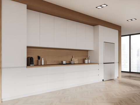 White and wooden kitchen corner with cabinets and fridge