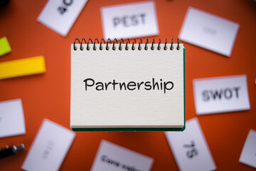 There is notebook with the word Partnership. It is as an eye-catching image.