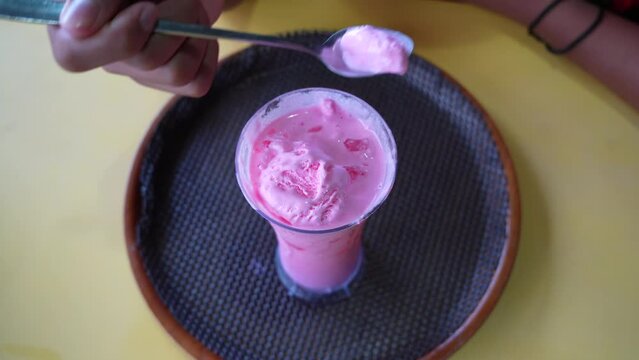 boy hand scooping strawberry ice cream in a glass