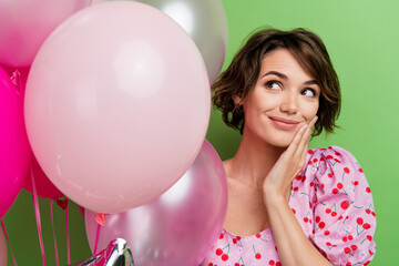 Photo of good mood nice woman with bob hairstyle dressed pink blouse palm on cheekbone look at bubbles isolated on green color background