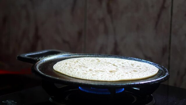 Wheat dosa on cast iron tawa. Steam coming from food while cooking on a stove. Traditional food.