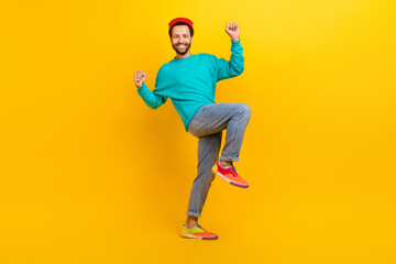 Full length photo of lucky man dressed turquoise pullover hat clenching fists dancing win gambling isolated on yellow color background